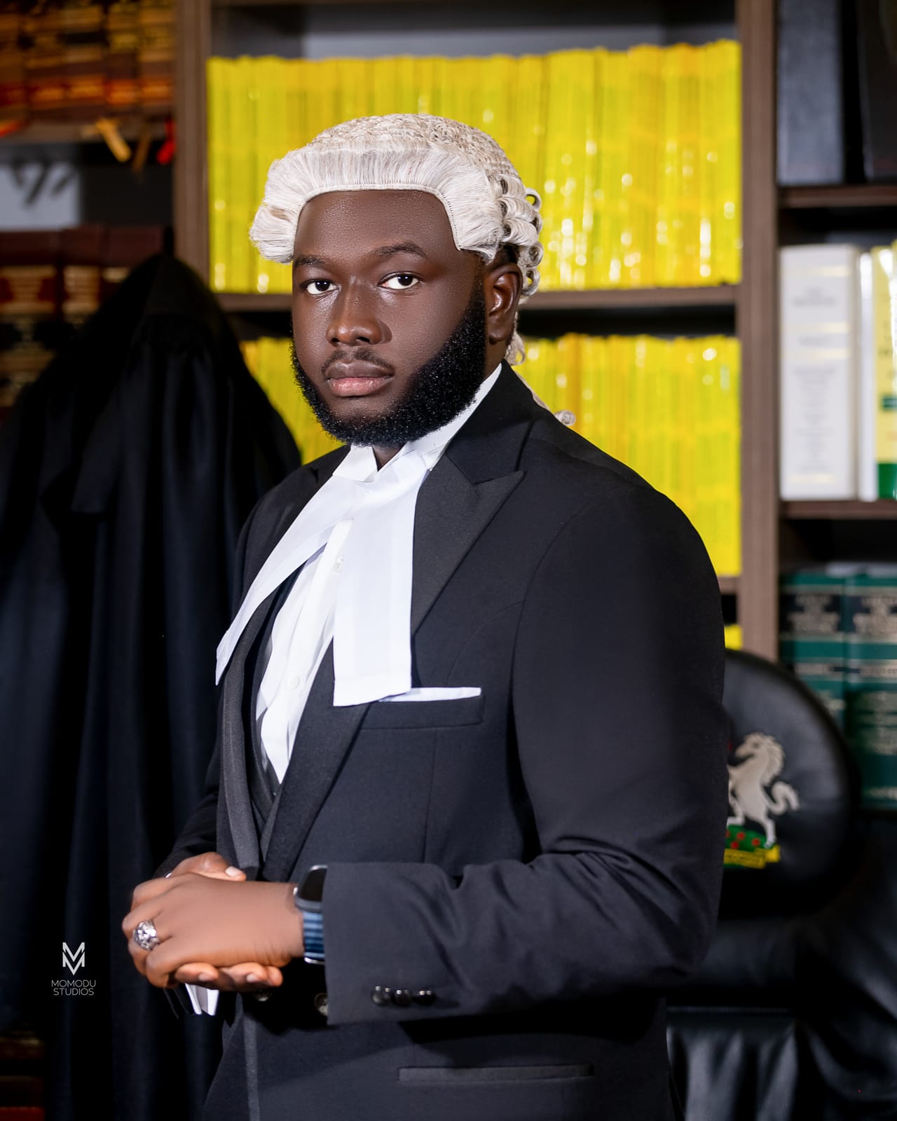 A new lawyer in wig and suit posed before shelves of law reports