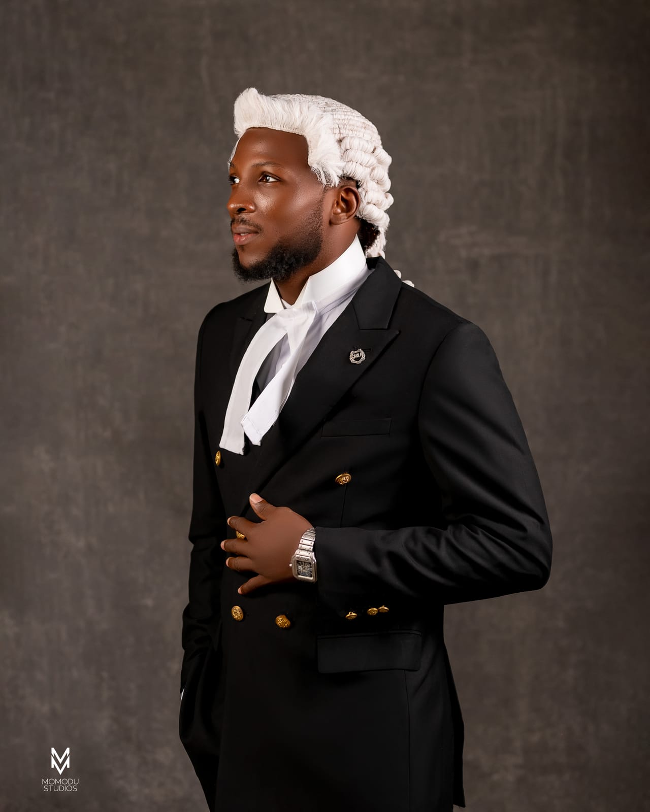 A new lawyer in wig and suit glancing to the side, grey backdrop